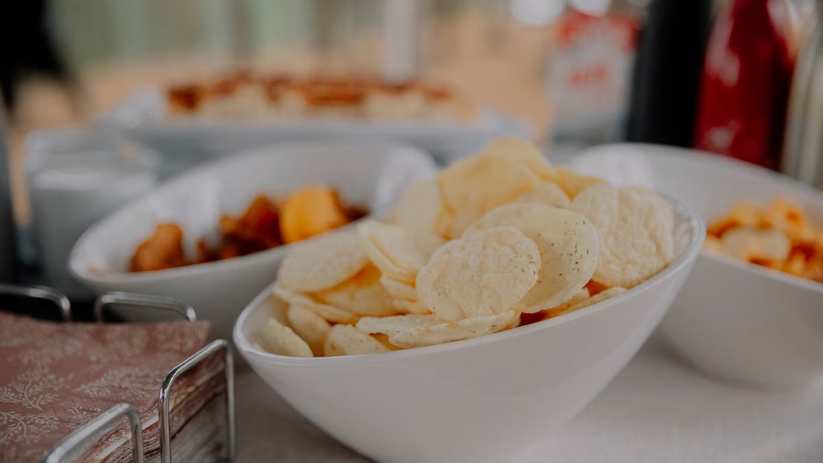 A variety of chips served in white bowls on a table, perfect for party snacks.